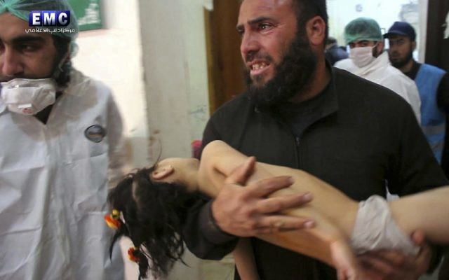 Following the suspected chemical attack, a man carries a child into a makeshift hospital in the town of Khan Sheikhoun. Photo: Edlib Media Center, via AP