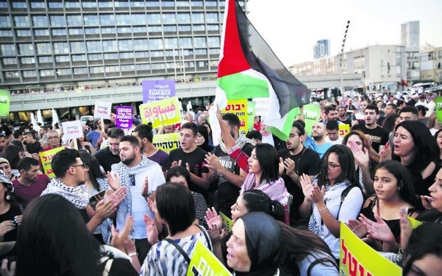 Israeli Arabs hold a Palestinian flag during Saturday's protest against the nation state law in Tel Aviv. Photo: AP Photo/Ariel Schalit Israeli Arabs hold a Palestinian flag during Saturday's protest against the nation state law in Tel Aviv. Photo: AP Photo/Ariel Schalit
