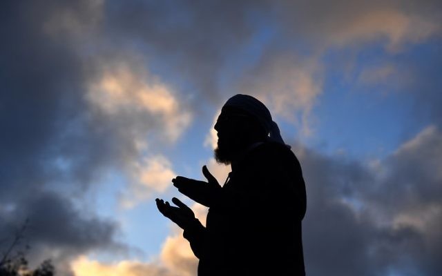 Mufti Zeeyad Ravat leads a prayer at the makeshift memorial by Christchurch's Al Noor Mosque.
Photo: AAP Image/Mick Tsikas