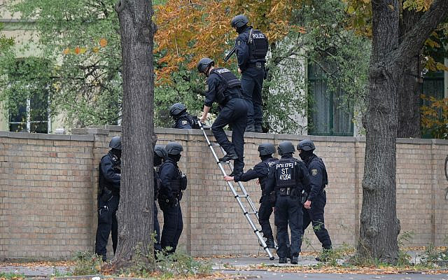 Police officers cross a wall at a crime scene in Halle, Germany, Oct. 9, 2019 after a shooting incident. (Sebastian Willnow/dpa via AP) Police officers cross a wall at a crime scene in Halle, Germany, Oct. 9, 2019 after a shooting incident. (Sebastian Willnow/dpa via AP)