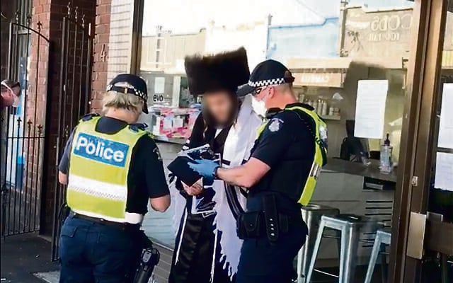 Police speak to an attendee of an illegal minyan in April. Photo: Facebook Police speak to an attendee of an illegal minyan in April. Photo: Facebook