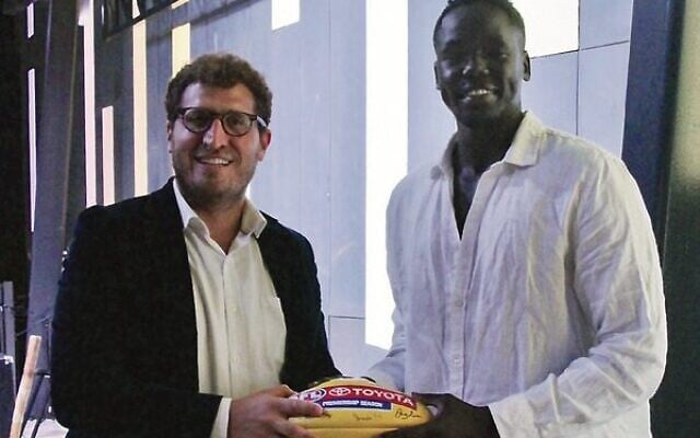 Reuben William (right) presenting a signed 2021 premiership season match ball to AFL Multicultural Program community ambassador Rabbi Gabi Kaltmann, at Pillars of Light at Federation Square. Reuben William (right) presenting a signed 2021 premiership season match ball to AFL Multicultural Program community ambassador Rabbi Gabi Kaltmann, at Pillars of Light at Federation Square.
