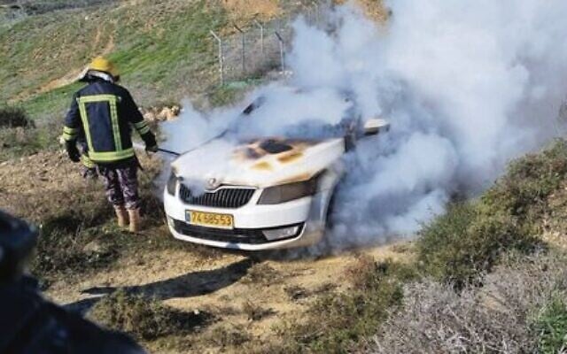A firefighter douses the flames in an Israeli car after it was allegedly set on fire by Jewish extremists near Givat Ronen last month. Photo: Courtesy, Yesh Din A firefighter douses the flames in an Israeli car after it was allegedly set on fire by Jewish extremists near Givat Ronen last month. Photo: Courtesy, Yesh Din
