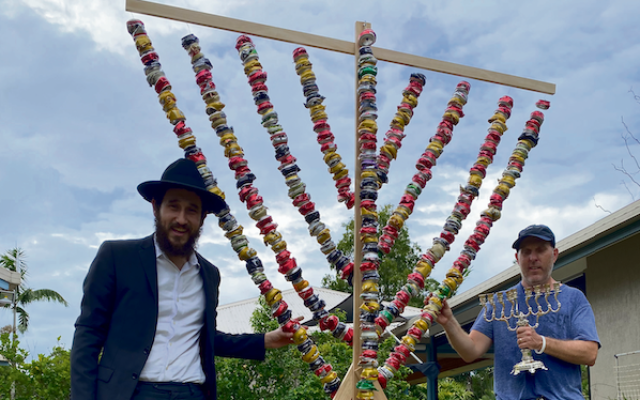 Rabbi Ari Rubin and Aaron Standley next to the menorah constructed out of recycled cans for the public lighting in Cairns on December 18. Photo: Ari Rubin Rabbi Ari Rubin and Aaron Standley next to the menorah constructed out of recycled cans for the public lighting in Cairns on December 18. Photo: Ari Rubin