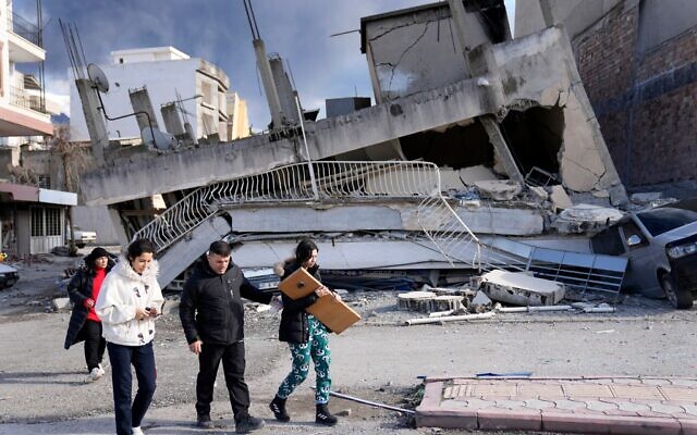 People pass a destroyed building, in Iskenderun town, southern Turkey. Photo: AP Photo/Hussein Malla via Times of Israel People pass a destroyed building, in Iskenderun town, southern Turkey. Photo: AP Photo/Hussein Malla via Times of Israel