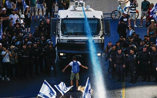 A person stands in front of a water cannon during a protest in Jerusalem on Monday. Photo: AP/Ariel Schalit A person stands in front of a water cannon during a protest in Jerusalem on Monday. Photo: AP/Ariel Schalit