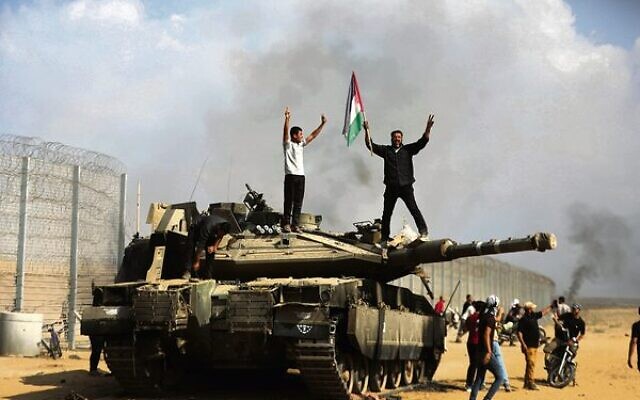Gazans celebrate on a destroyed Israeli tank at the Israel-Gaza border fence on October 7.
Photo: AP/Yousef Masoud Gazans celebrate on a destroyed Israeli tank at the Israel-Gaza border fence on October 7.
Photo: AP/Yousef Masoud