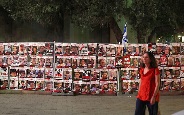 Illustrative: A woman walks past portraits of Israelis taken hostage by Palestinian terrorists in the October 7 attack, during a demonstration calling for their release in Tel Aviv on November 13, 2023. (The Times of Israel: Ahmad Gharabli/AFP) Illustrative: A woman walks past portraits of Israelis taken hostage by Palestinian terrorists in the October 7 attack, during a demonstration calling for their release in Tel Aviv on November 13, 2023. (The Times of Israel: Ahmad Gharabli/AFP)