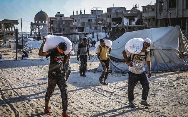 Gazans with bags of flour in Khan Younis after humanitarian aid trucks arrive via the Israeli-controlled Kerem Shalom crossing on July 24. Photo: Abed Rahim Khatib/Flash90 Gazans with bags of flour in Khan Younis after humanitarian aid trucks arrive via the Israeli-controlled Kerem Shalom crossing on July 24. Photo: Abed Rahim Khatib/Flash90