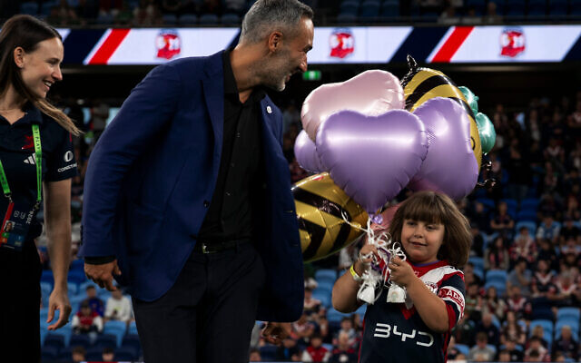 Alex Ryvchin and Summer Bee walk onto the field for the Sydney Roosters opener. Alex Ryvchin and Summer Bee walk onto the field for the Sydney Roosters opener.
