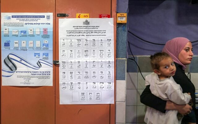 A woman carrying a child at a polling station in the southern bedouin city of Rahat on October 27, 2026. Photo: Hazem Bader/AFP A woman carrying a child at a polling station in the southern bedouin city of Rahat on October 27, 2026. Photo: Hazem Bader/AFP
