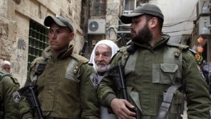 رجل فلسطيني يقف وراء قوات الامن الاسرائيلية في زقاق متجه الى مسجد الاقصى في القدس الشرقية 25 فبراير 2014 (أ ف ب)