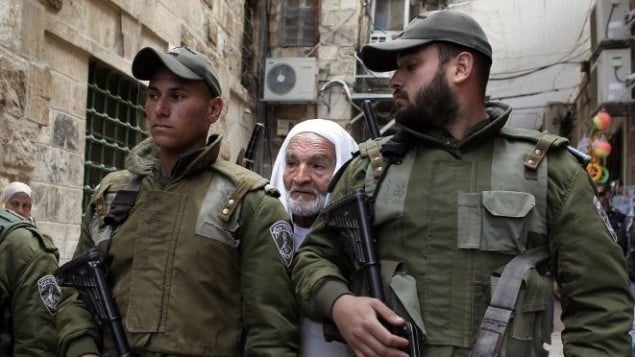 رجل فلسطيني يقف وراء قوات الامن الاسرائيلية في زقاق متجه الى مسجد الاقصى في القدس الشرقية 25 فبراير 2014 (أ ف ب)
