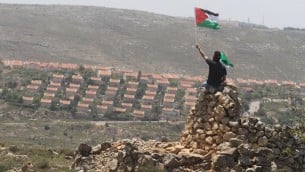 رجل يلوح بالعلم الفلسطيني امام مستوطنة عوفرابجانب رامالله (عصام ريماوي/ فلاش 90)