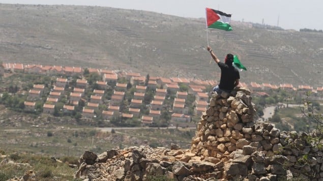 رجل يلوح بالعلم الفلسطيني امام مستوطنة عوفرابجانب رامالله (عصام ريماوي/ فلاش 90)