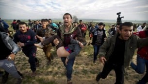 متظاهرون فلسطينيون في قطاع غزة يحملون صبي مصاب خلال اشتباكات مع قوات الجيش الاسرائيلي 21.02.2014 (أ ف ب )