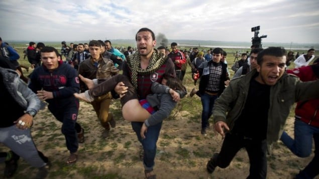 متظاهرون فلسطينيون في قطاع غزة يحملون صبي مصاب خلال اشتباكات مع قوات الجيش الاسرائيلي 21.02.2014 (أ ف ب )