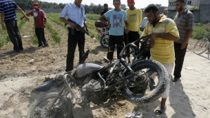 فلسطينيون حول دراجة نارية اصيبت بنيران اسرائيلية في دير البلح في غزة 2012 (عبد الرحيم خطيب / فلاش 90)