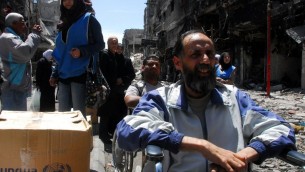 صورة صادرة عن وكالة الانباء السورية الرسمية (سانا) يوم 24 أبريل 2014، لسوريين  ينتظرون صناديق من المساعدات الغذائية التي يتم توزيعها من قبل وكالة إغاثة الأمم المتحدة (الأونروا) في مخيم للاجئين الفلسطينيين اليرموك جنوب سوريا . AFP PHOTO / HO / SANA