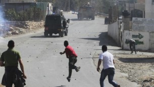صورة توضيحية فلسطينيون يرمون الحجارة على سيارة الجيش الاسرائيلي (عصام ريماوي/ فلاش ٩٠)