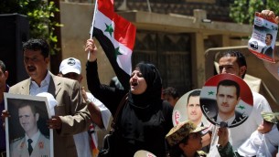 صورا للرئيس السوري بشار الاسد خلال تظاهرة لدعم إعادة انتخابه في 24 مايو 2014 خارج السفارة السورية في العاصمة اليمنية صنعاء.  AFP PHOTO / MOHAMMED HUWAIS