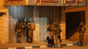 جنود اسرائيليين في محاولة لفتح ابواب متجر مغلقة خلال عملية في أحد شوارع بلدة الخليل بالضفة الغربية  17 يونيو 2014 . AFP PHOTO / حازم بدر