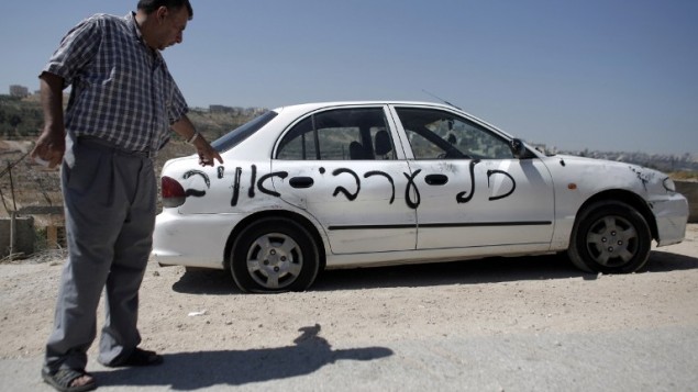رجل فلسطيني يشير الى واحدة من عشر سيارات التي تم رشها مع الشعارات العنصرية التي تقرأ في العبرية "كل العرب أعداء" في حي القدس شرق بيت حنينا 23 يونيو 2014 AFP PHOTO / AHMAD GHARABLI رجل فلسطيني يشير الى واحدة من عشر سيارات التي تم رشها مع الشعارات العنصرية التي تقرأ في العبرية "كل العرب أعداء" في حي القدس شرق بيت حنينا 23 يونيو 2014 AFP PHOTO / AHMAD GHARABLI