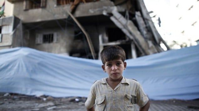 طفل فلسطيني يقف أمام القماش المشمع الملفوف حول مبنى دمر في أعقاب ضربة جوية اسرائيلية 14 يوليو 2014 في مدينة غزة. AFP PHOTO / THOMAS COEX طفل فلسطيني يقف أمام القماش المشمع الملفوف حول مبنى دمر في أعقاب ضربة جوية اسرائيلية 14 يوليو 2014 في مدينة غزة. AFP PHOTO / THOMAS COEX