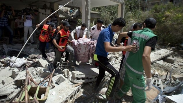 مسعفون فلسطينيون يحملون جثمان جليلة عياد، امرأة مسيحية وجدت تحت أنقاض منزلها، 27 يوليو 2014. AFP PHOTO / MAHMUD HAMS