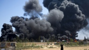 رجل فلسطيني، يقف امام اللهيب الصاعد من مصنع الكهرباء الوخيد الذي يوصل كهرباء لاهل غزة، بعد غارة اسرائيلية 29 يوليو 2014 (مخمود حمص/ أ ف ب)