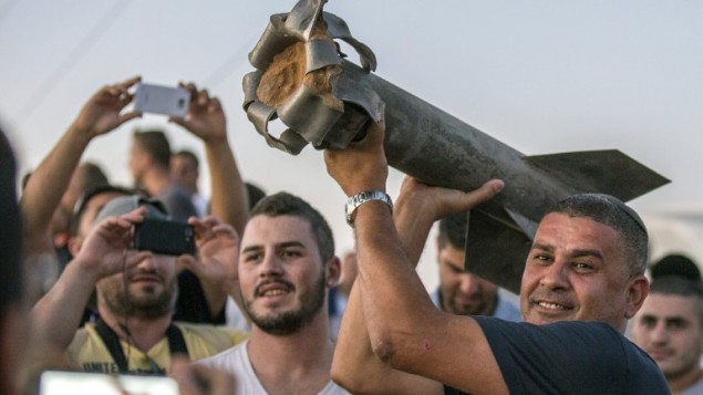 مواطنون اسرائيليون معظمهم من مدينة سديروت في جنوب إسرائيل، يحملون بقايا صاروخ،  13 يوليو عام 2014. AFP PHOTO / JACK GUEZ