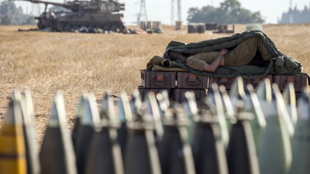 جندي إسرائيلي ينام على صندوق ذخيرة قرب المدفعية 155MMالمتمركزة AFP PHOTO / JACK GUEZ على طول الحدود الإسرائيلية الجنوبية مع قطاع غزة في أعقاب الغارات الجوية الاسرائيلية على قطاع غزة يوم 11 يوليو 2014.