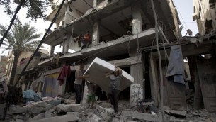 فلسطينيون يحاولون استعادة فراش من تحت أنقاض مبنى مدمر إثر ضربة عسكرية اسرائيلية في مدينة غزة يوم 12 يوليو 2014  AFP PHOTO / MAHMUD HAMS
