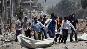 مسعفون يقومون بإخلاء جثة من منطقة الشجاعية شرق غزة  20 يوليو 2014. AFP PHOTO / MAHMUD HAMS