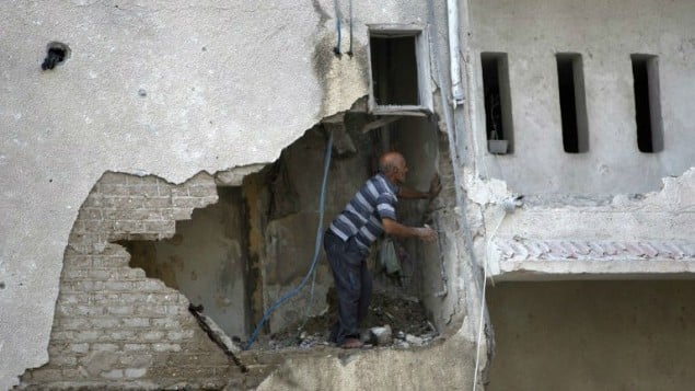 رجل فلسطيني يتفحص الاضرار لبيت هدم جزئيا جراء غارة اسرائيلية 19 يوليو 2014 (أ ف ب)