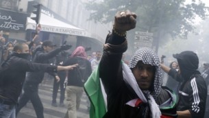 متظاهر يرتدي الكوفية والعلم الفلسطيني  13 يوليو 2014 في باريس، خلال مظاهرة ضد اسرائيل ودعما للسكان في قطاع غزة.  AFP/KENZO TRIBOUILLARD