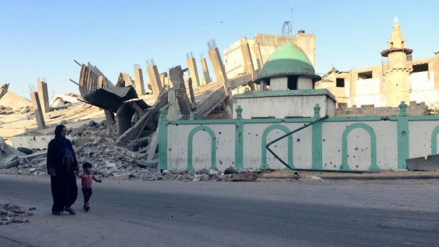 امرأة فلسطينية وطفل يمشيان بجانب المسجد العمري الذي دمر في 12 أغسطس  2014 في جباليا، شمال قطاع غزة. مزق صاروخ اسرائيلي خلال سقف مقبب  من الحجر الرملي. دمرت إصابة مباشرة المسجد العمري في جباليا. ويعتقد الموقع أن يضم مسجدا بني في القرن السابع وأجزاء منه تعود إلى القرن الرابع عشر AFP PHOTO/ROBERTO SCHMIDT