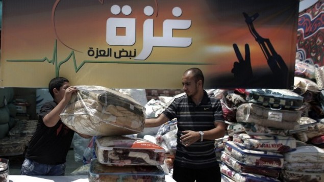فلسطينيون يجمعون السلع والبطانيات في القدس الشرقية، 14 أغسطس عام 2014، ليتم إرسالها وتوزيعها مع الصليب الأحمر للمحتاجين في قطاع غزة.  AFP PHOTO / AHMAD GHARABLI