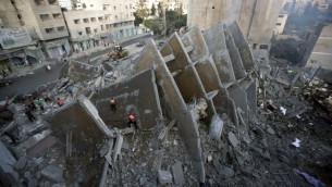 سكان فلسطينيون وعناصر الاسعاف يتفقدون بقايا المبنى الذي دمرته الغارات الاسرائيلية والتي اسفرت عن مقتل 2 واصابة 20, مدينة غزة 26 اغسطس 2014 AFP PHOTO/MAHMUD HAMS