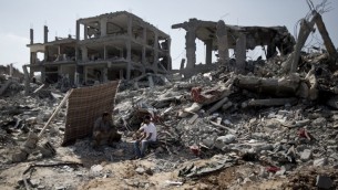 رجال فلسطينيون يتفقدون الدمار حول بيوتهم خلال الهدنة  في حي التفاح, غزة. 6 اغسطس 2014  AFP PHOTO / MAHMUD HAMS