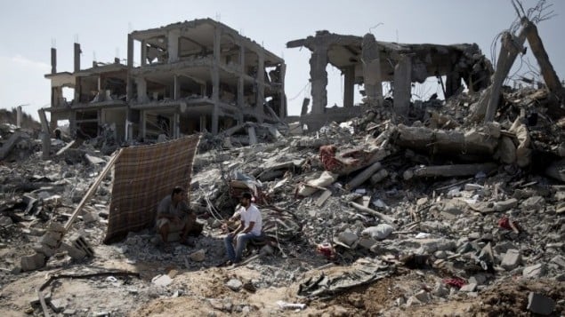 رجال فلسطينيون يتفقدون الدمار حول بيوتهم خلال الهدنة  في حي التفاح, غزة. 6 اغسطس 2014  AFP PHOTO / MAHMUD HAMS