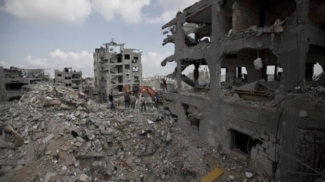 فلسطينيون بين انقاض المباني المدمرة في جزء من حي التفاح، مدينة غزة اثناء وقف إطلاق النار 6 أغسطس 2014. AFP PHOTO / MAHMUD HAMS فلسطينيون بين انقاض المباني المدمرة في جزء من حي التفاح، مدينة غزة اثناء وقف إطلاق النار 6 أغسطس 2014. AFP PHOTO / MAHMUD HAMS