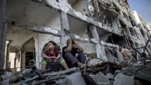 أخوان فلسطينيان يجلسان على أنقاض بيتهم في بيت حانون 5 أغسطس 2014 (AFP/MARCO LONGARI)