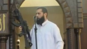 Screenshot from MEMRI video of Gaza imam brandishing rifle during a sermon on Augusyt 29, 2014.
