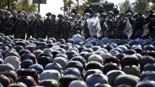 قوات الأمن الإسرائيلية تقف أمام المصلين المسلمين الفلسطينيين وهم يؤدون صلاة الجمعة التقليدية في شارع خارج البلدة القديمة في القدس الشرقية  24 تشرين الأول 2014  
AFP PHOTO / THOMAS COEX