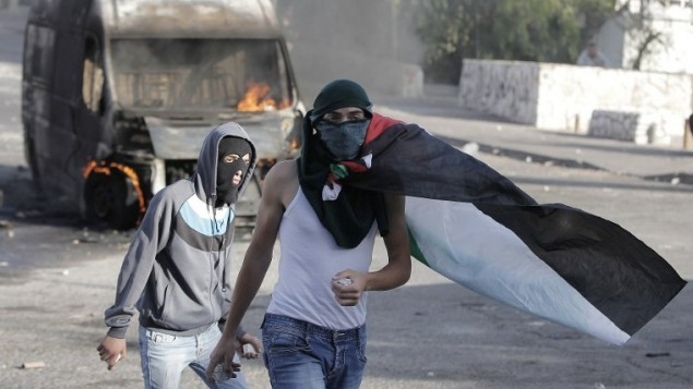 ملثم فلسطيني يلقي حجارة أثناء اشتباكات مع قوات الأمن الإسرائيلية في القدس الشرقية، 30 أكتوبر 2014 AFP/Ahmad Gharabli