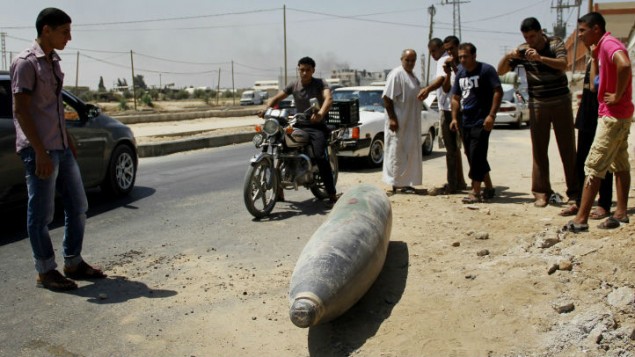 فلسطينيون ينظرون الى ذخيرة غير منفجرة في شارع في دير البلح في وسط قطاع غزة 01 أغسطس 2014 Mostafa Ashqar/FLASH90 فلسطينيون ينظرون الى ذخيرة غير منفجرة في شارع في دير البلح في وسط قطاع غزة 01 أغسطس 2014 Mostafa Ashqar/FLASH90