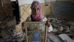 أحد أقارب عبد الرحمن الشلودي وهو فلسطيني قتل اثنين من الاسرائيليين مع سيارته الشهر الماضي، تحمل صورة له داخل منزل عائلته  في شرقي القدس حي سلوان بعد ان هدمت السلطات الاسرائيلية المنزل. 19 نوفمبر 2014   AFP PHOTO/AHMAD GHARABLI