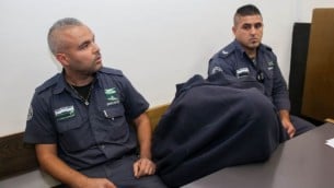 شرطي حرس الحدود المتهم بإطلاق النار وقتل فتى فلسطيني في سن المراهقة   15 مايو في بيتونيا خلال مظاهرات يوم النكبة. الشرطي في الوسط مغطيا وجهه في  المحكمة  في القدس 23 نوفمبر، 2014. (فلاش 90)