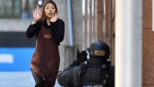 أحد الرهائن تركض  نحو الشرطة من مقهى في سيدني في 15 ديسمبر، 2014 AFP/SAEED KHAN
